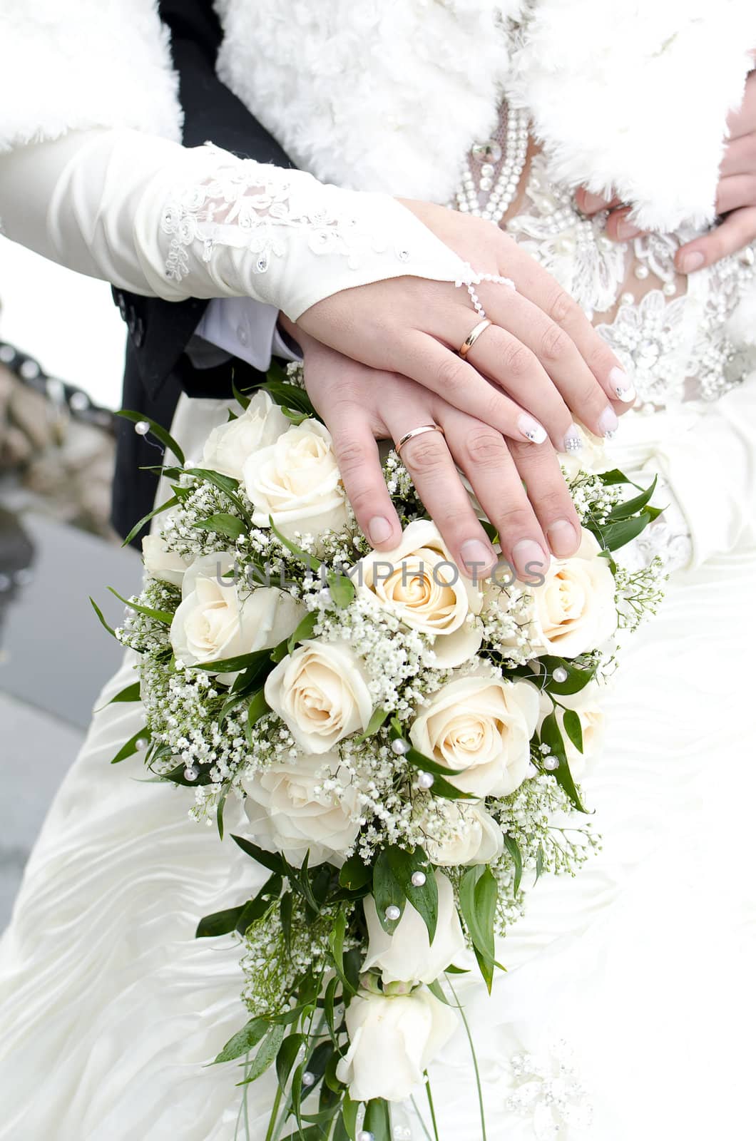 Bridal bouquet of flowers with hands of newlyweds