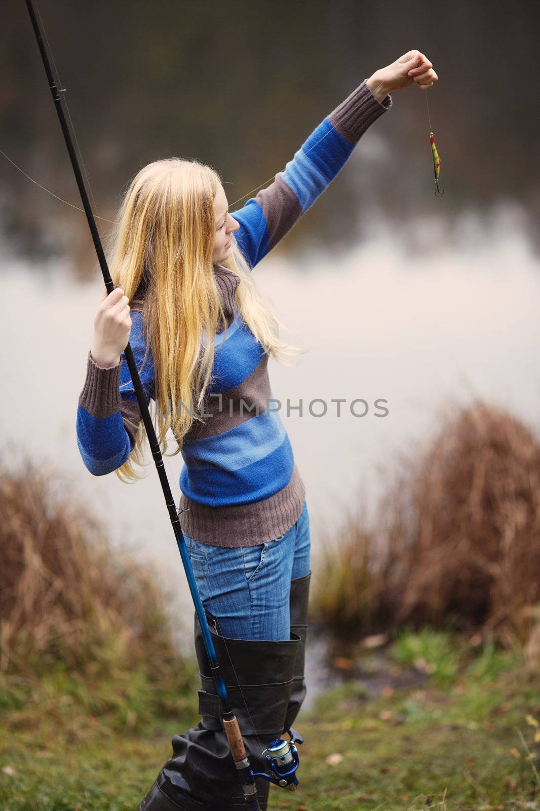 beautiful blond girl fishing in pond at autumn