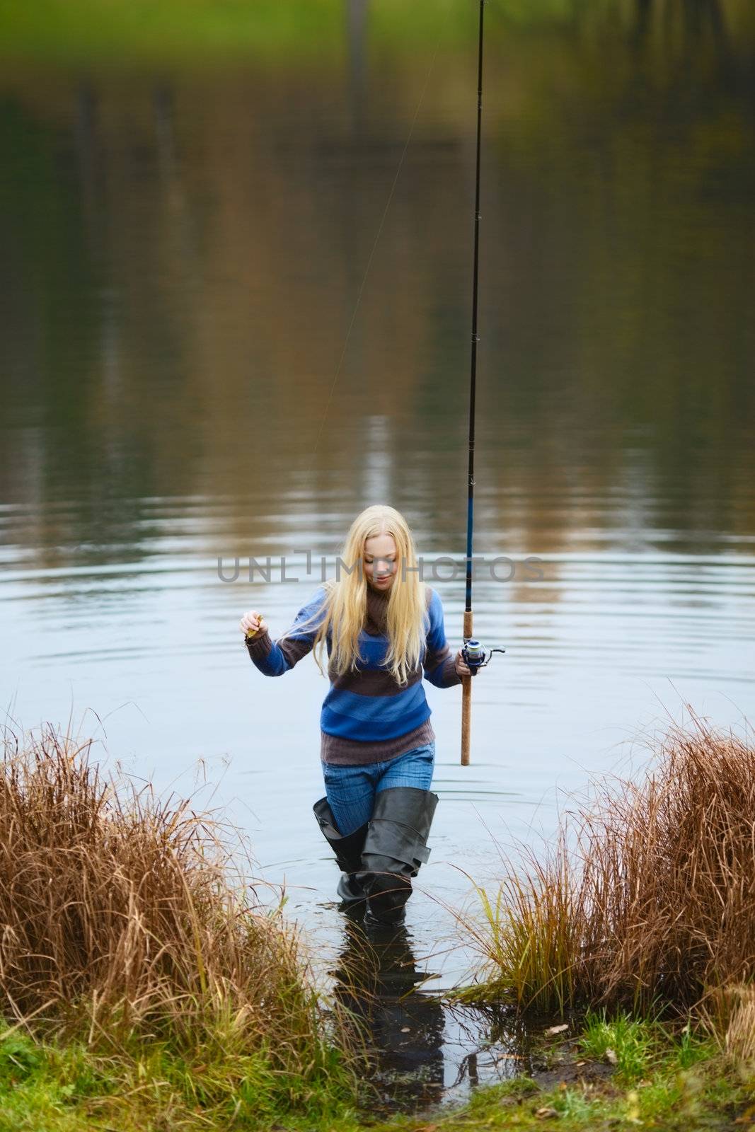 beautiful blond girl fishing in pond at autumn