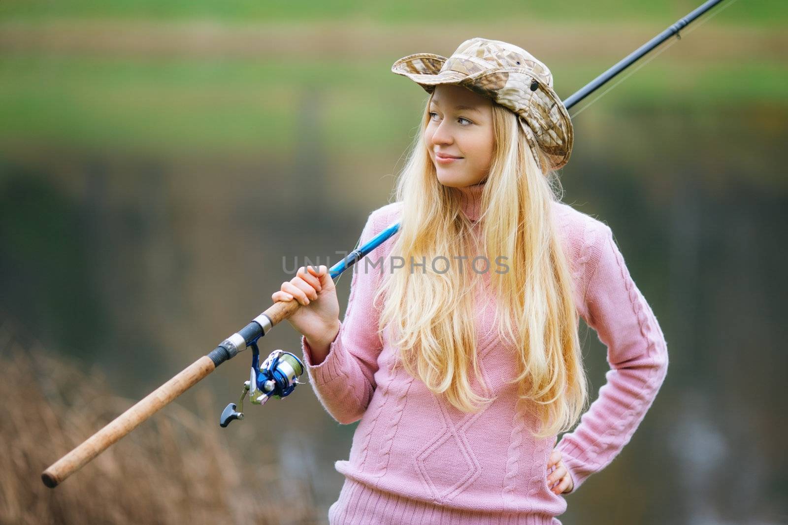 beautiful blond girl fishing in pond at autumn