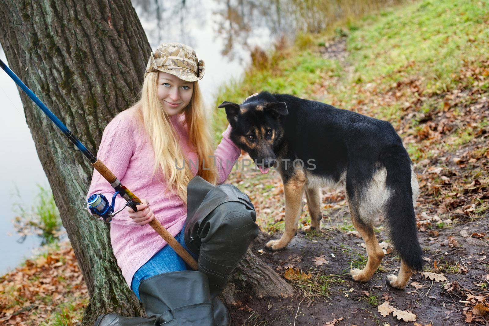 girl with fihing rod and black dog at autumn