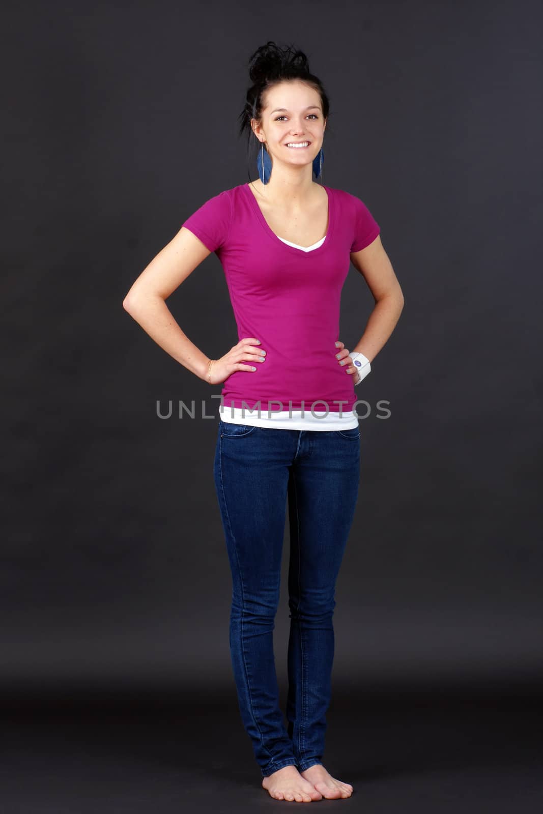 Full body shot of a natural beauty: casual young woman or student, in jeans and pink T-shirt over black background.