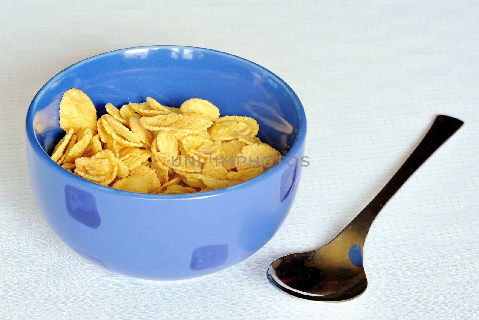 Cereal flakes in a blue bowl on white background