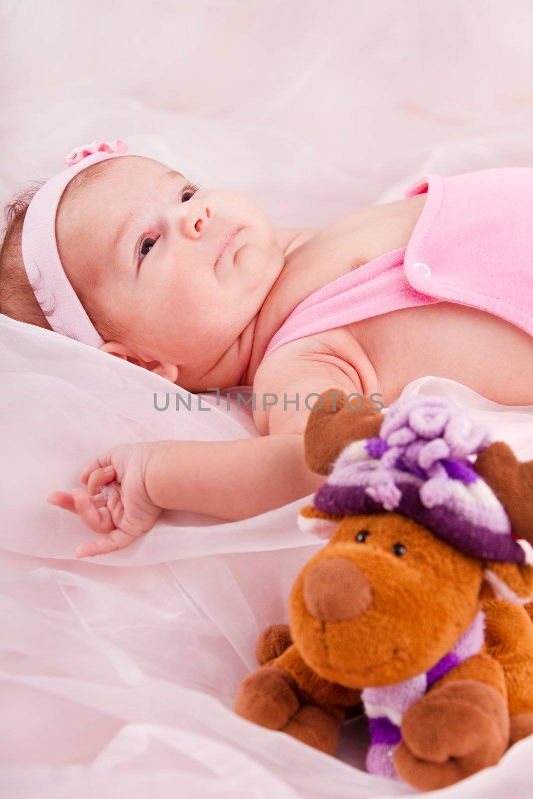 View of a newborn baby on smooth bed with toy.