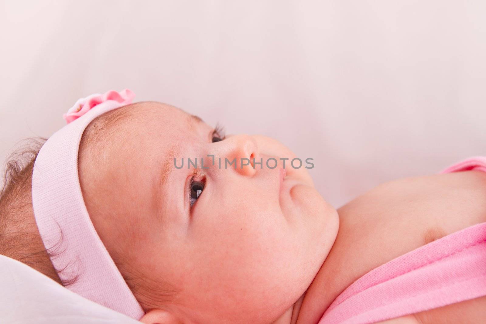 View of a newborn baby on smooth bed.
