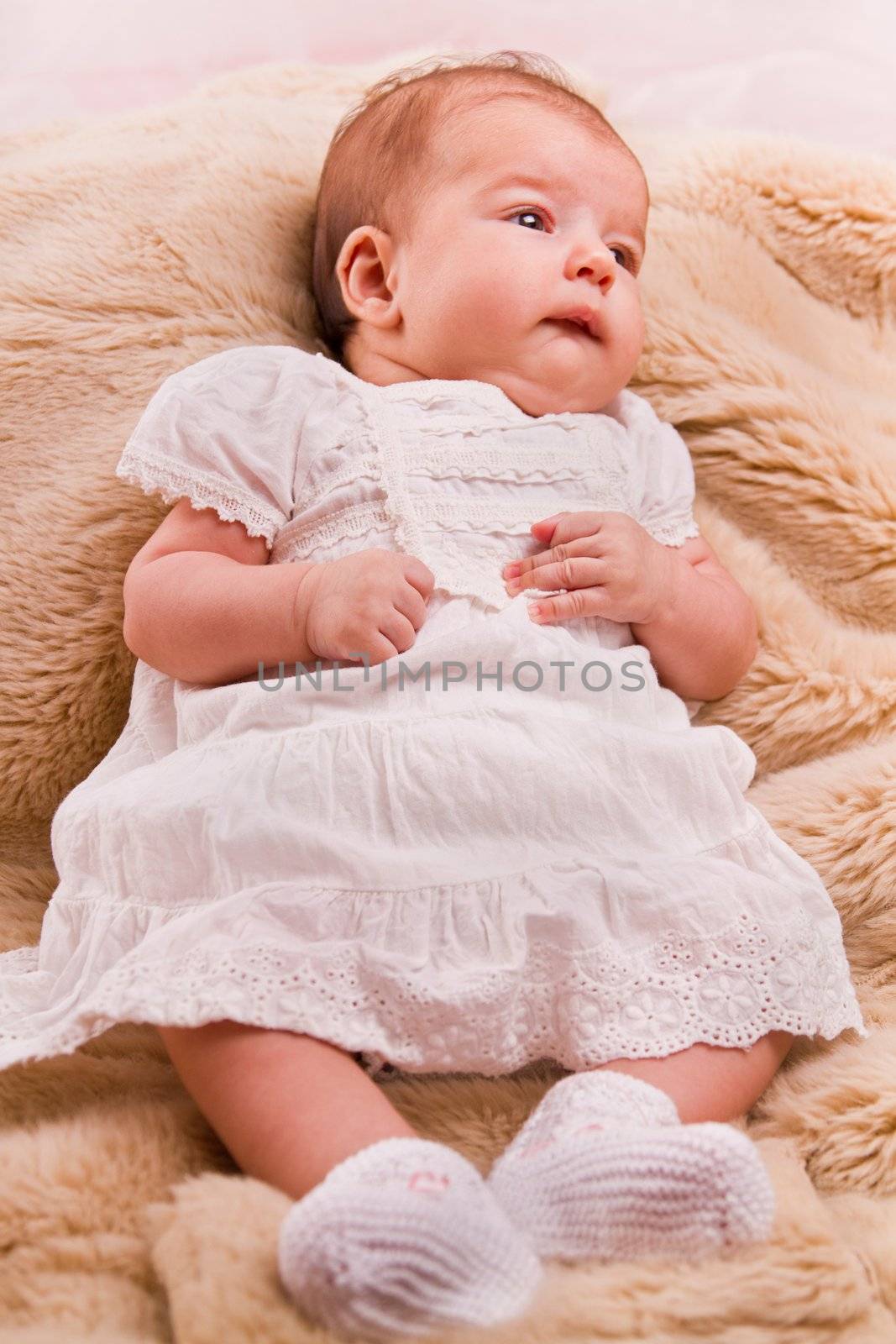 View of a newborn baby on a smooth bed.