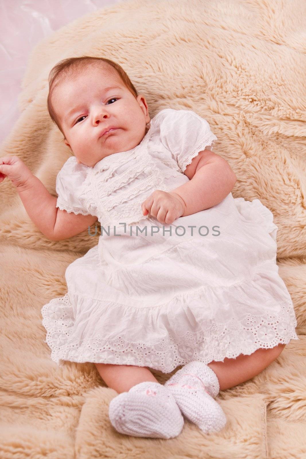 View of a newborn baby on a smooth bed.