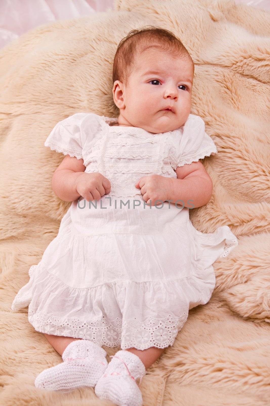 View of a newborn baby on a smooth bed.