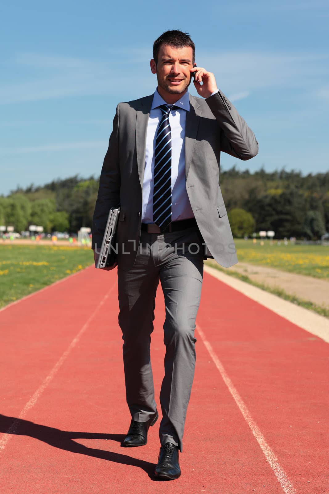 businessman with phone and laptop on a running track