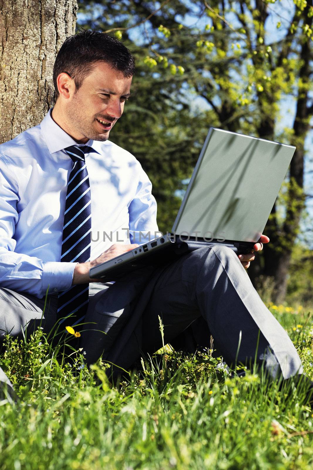 businessman working with laptop in a park in summer