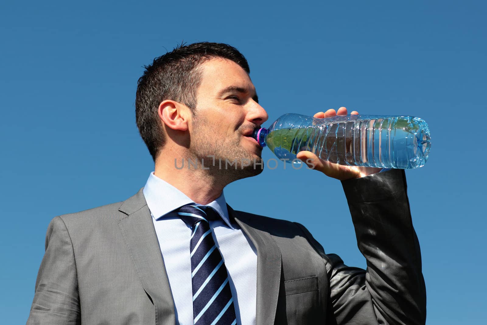 handsome man drinking water with bottle in blue sky