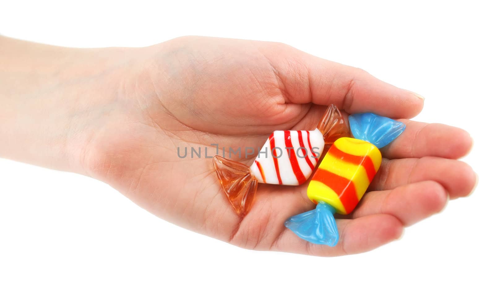 Woman's hand gives two colored candy isolated on a white background