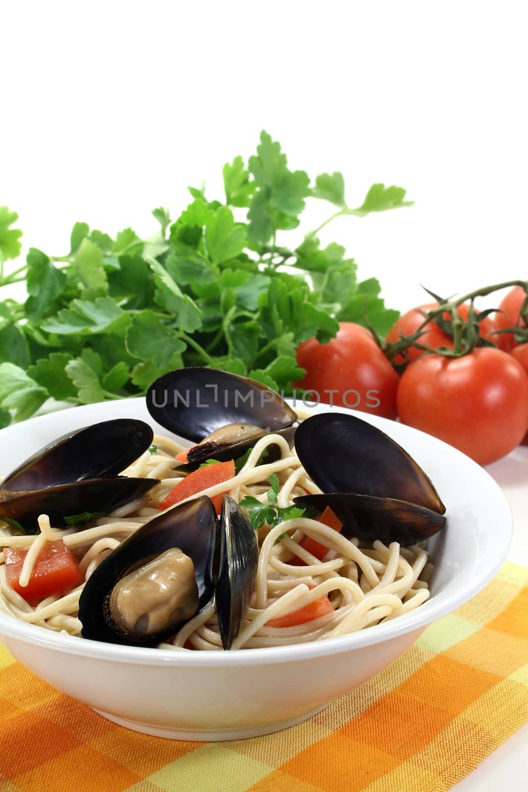 Spaghetti with tomatoes, mussels and parsley on a light background