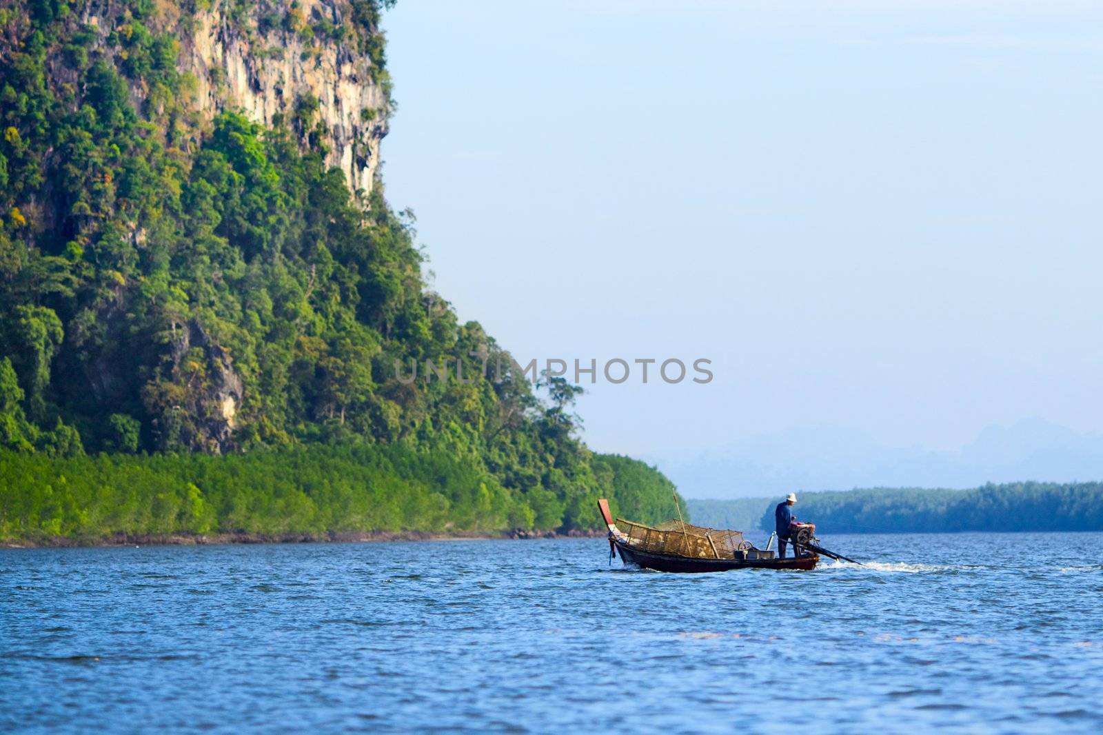 tall cliff in sea and fisherman in boat, Andaman Sea, Thailand