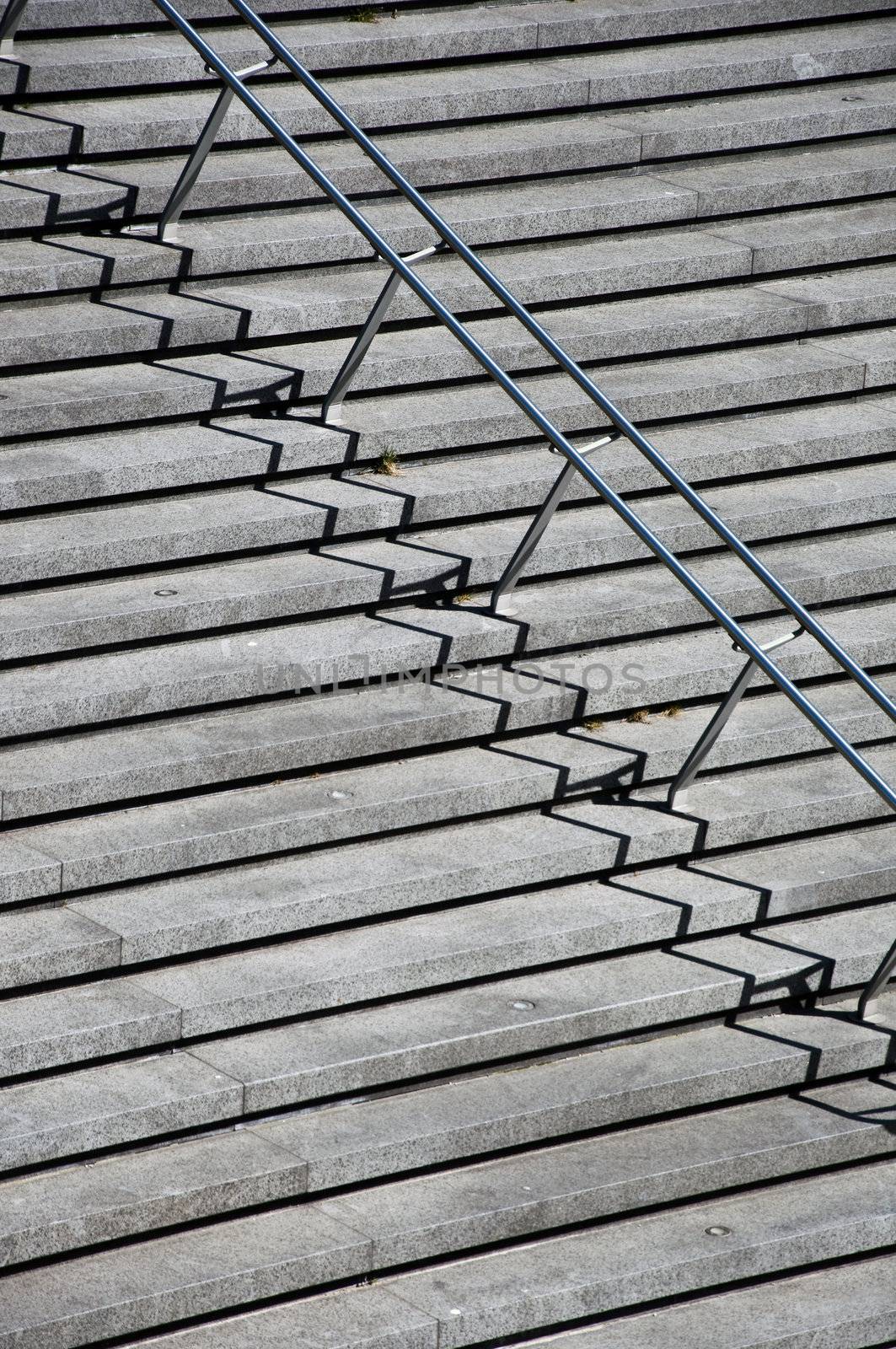 Rung of the Stairs with stainless steel handrails. A fragment with a clear shadow. The simple geometry.