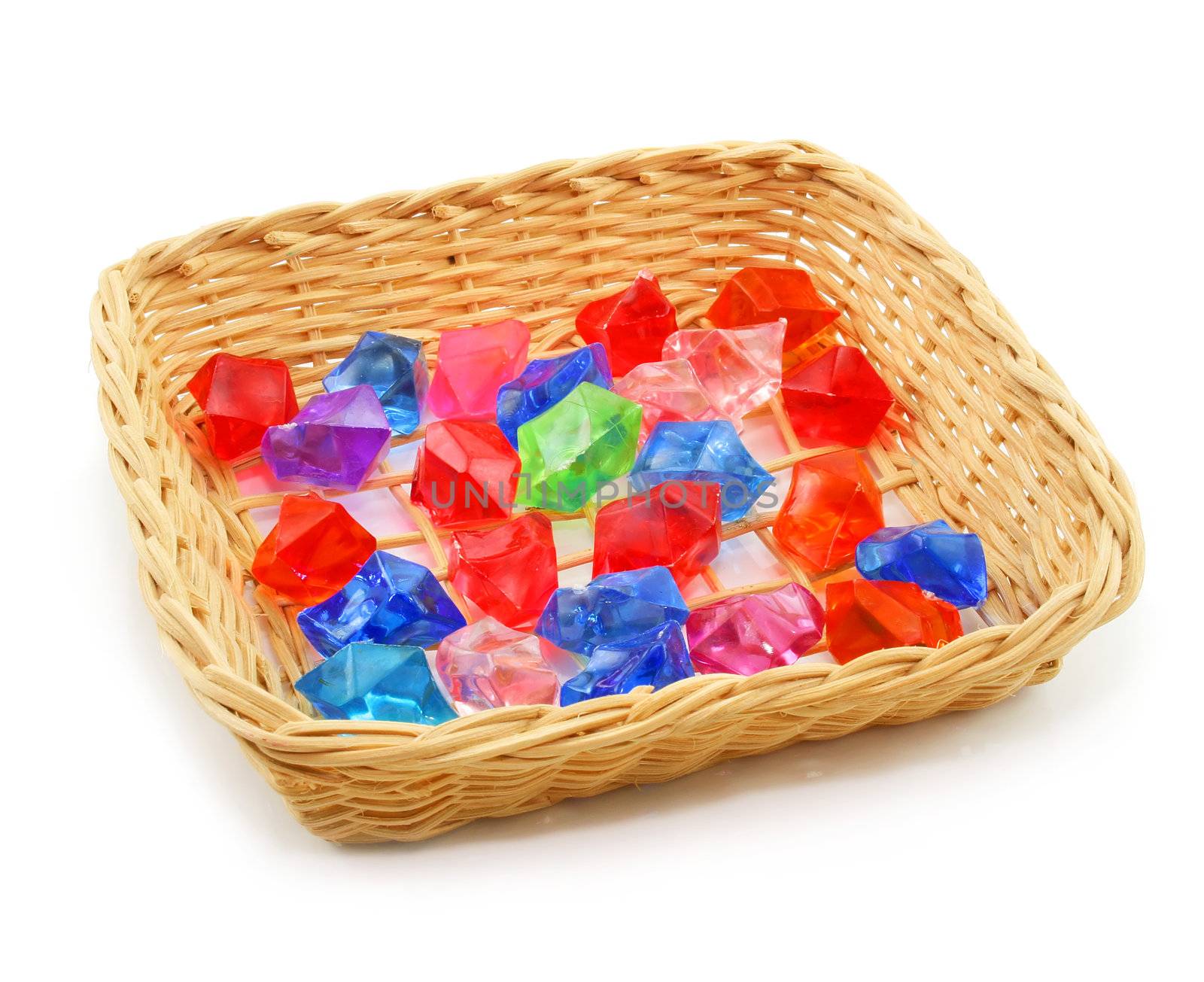 Colored assorted gemstones in wooden basket isolated on a white background
