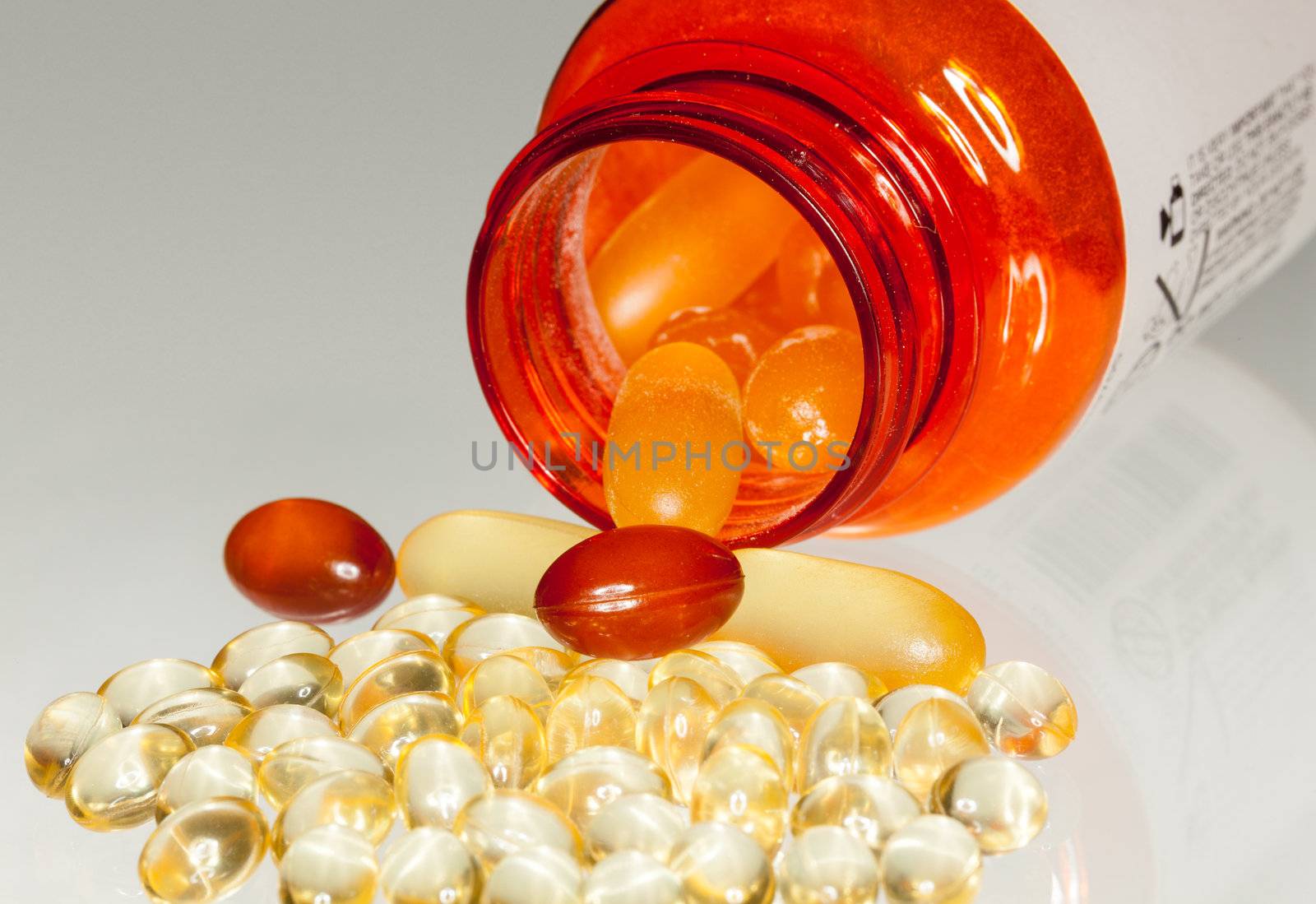 Various sorts of fish oil tablets spilling from prescription bottle onto table