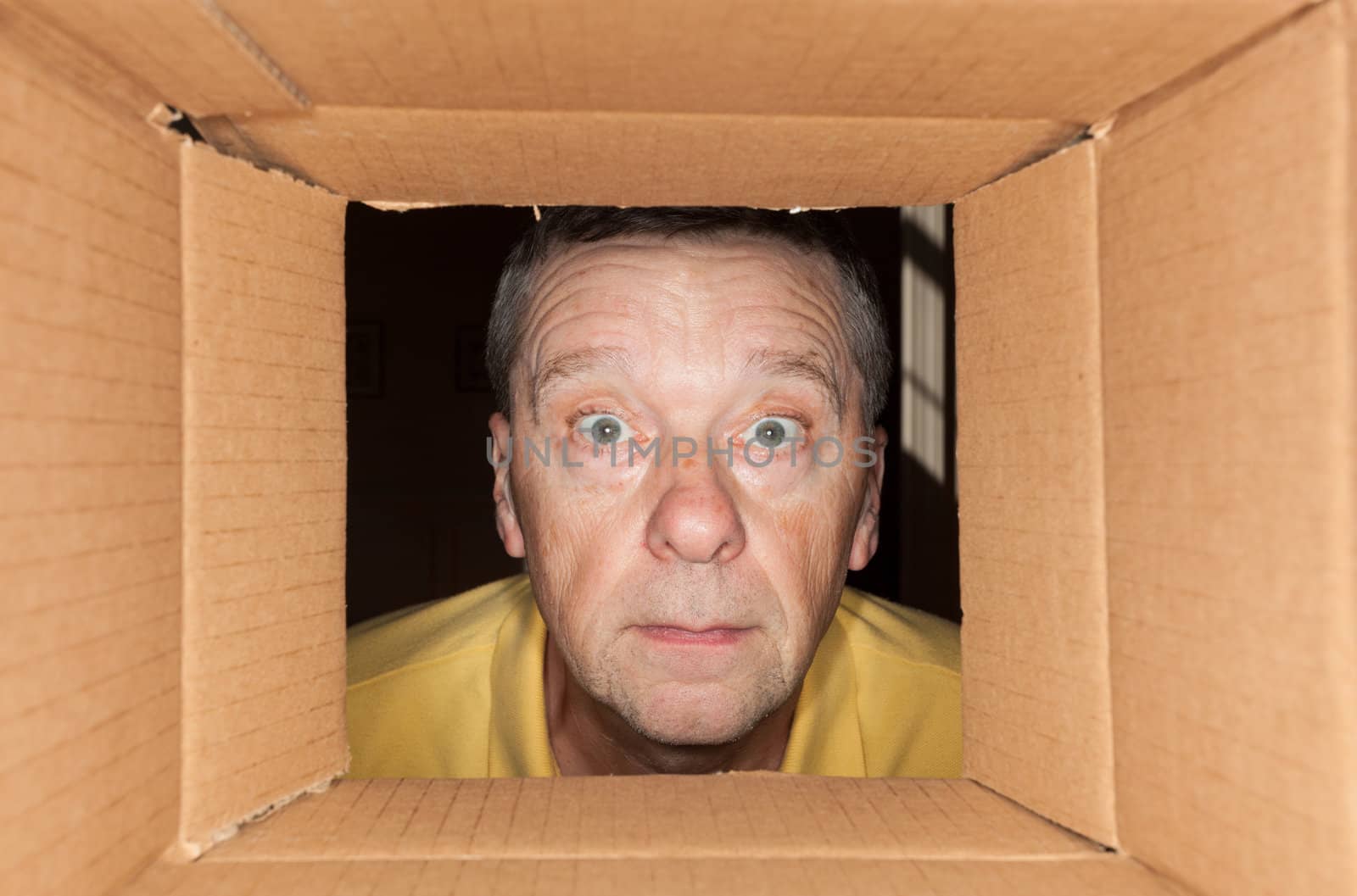 Senior caucasian man looking directly into a cardboard box and being worried