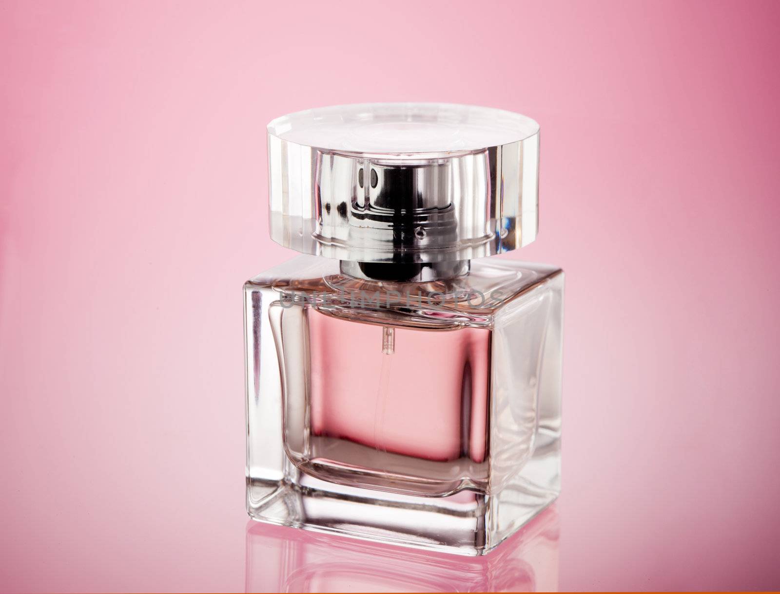 glass of perfume over abstract pink background