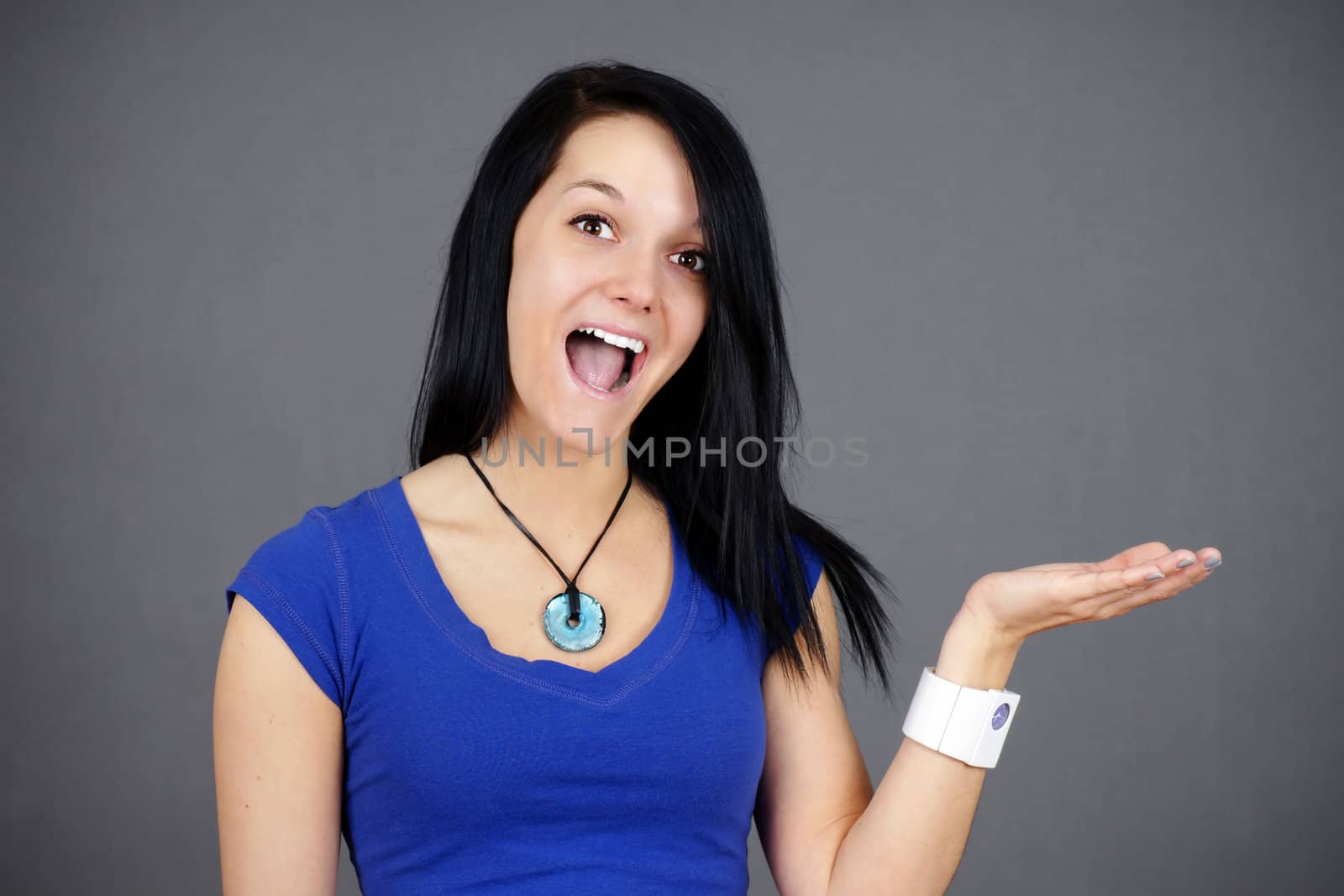 Portrait of a very surprised young woman or student holding something up in her hand, fun advertisement.