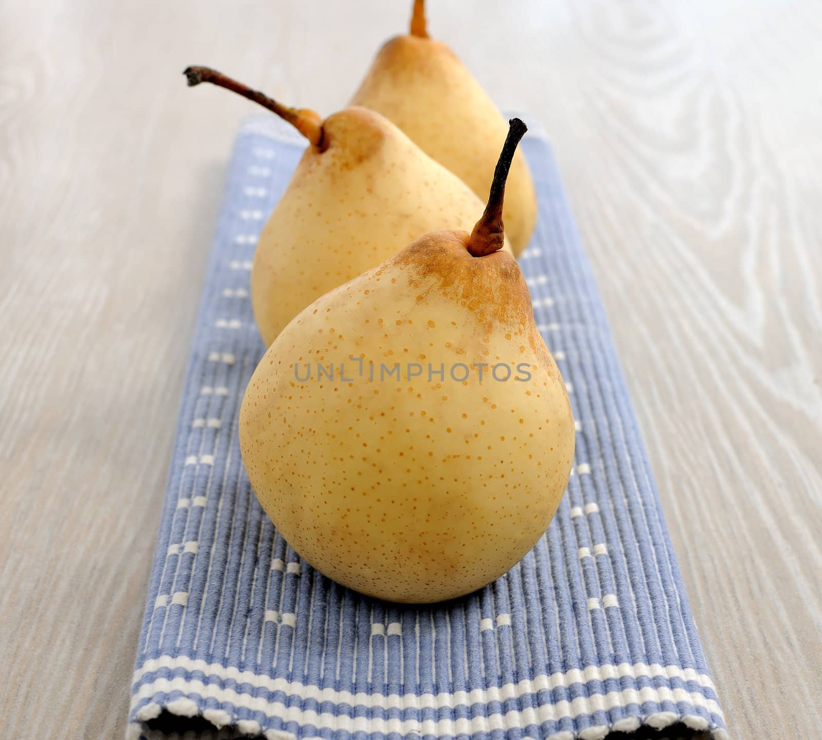 Three ripe yellow pears in a number on a napkin