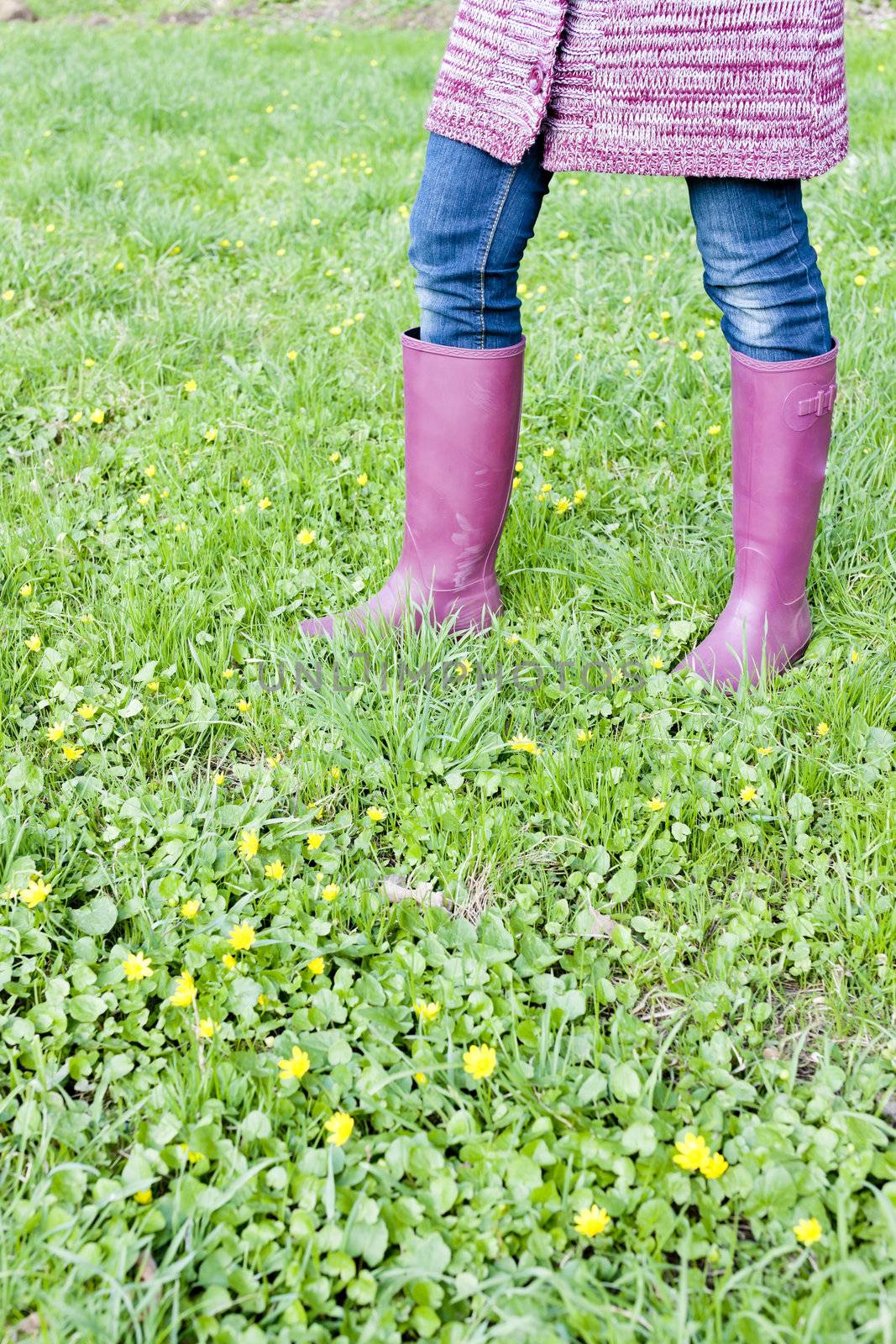 detail of woman wearing rubber boots on spring meadow