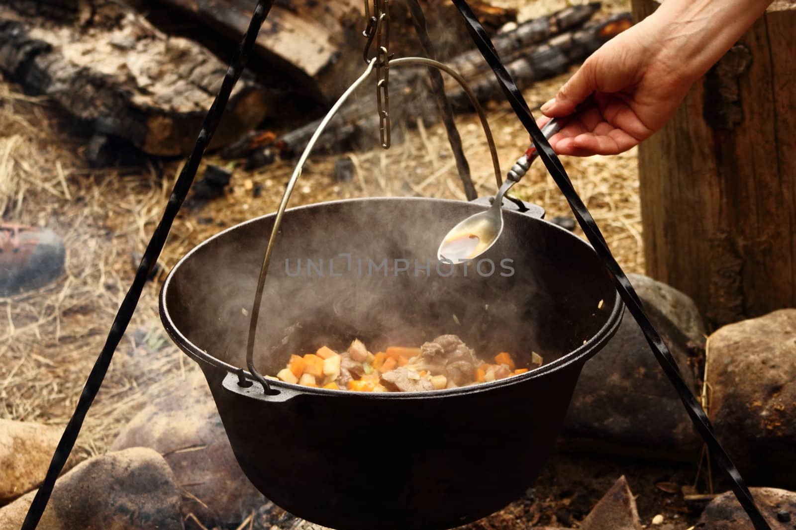 cooking outdoors in a big caldron suspended above the fireplace