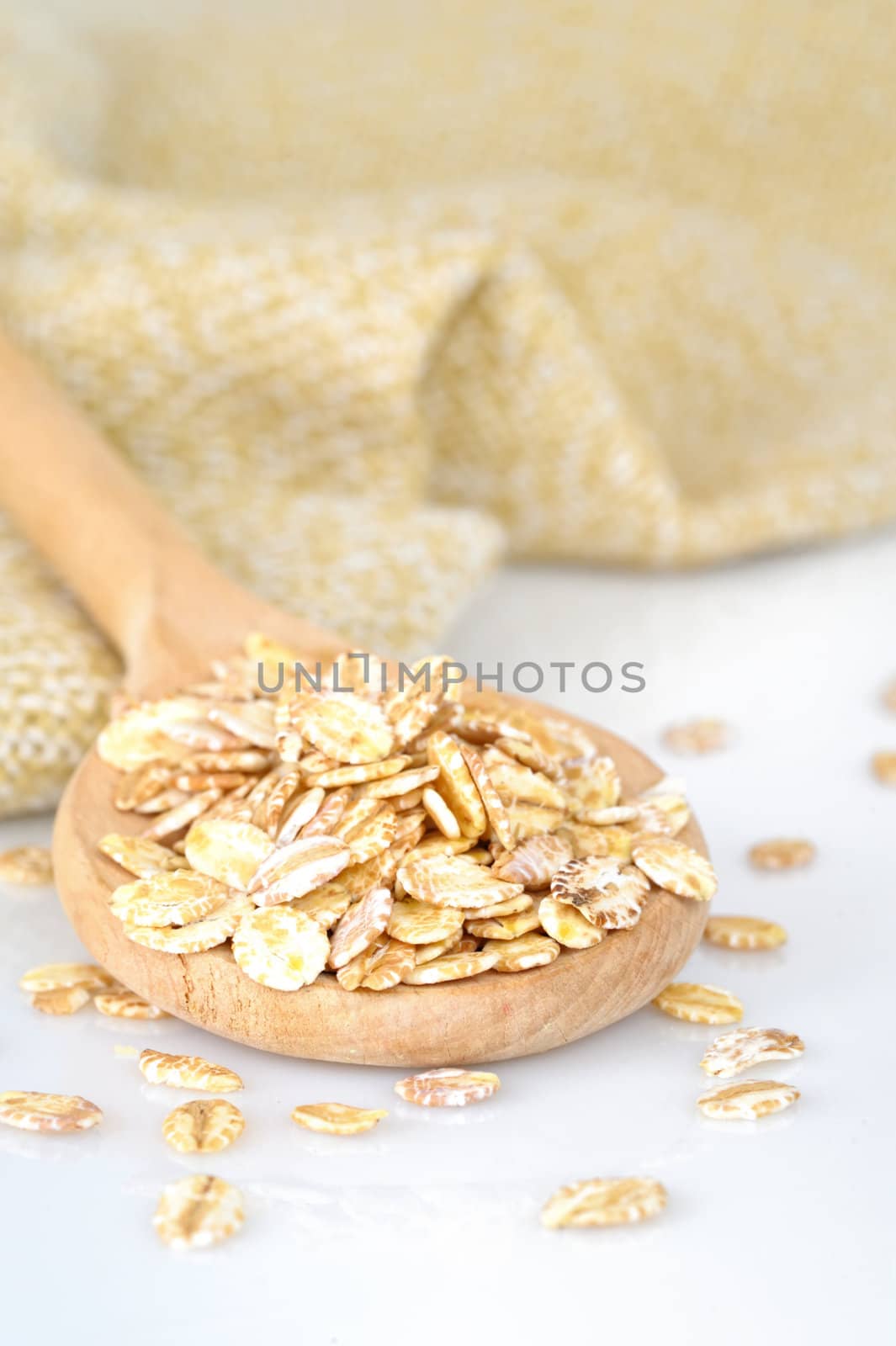 close up of oat flakes in wooden spoon  by manaemedia