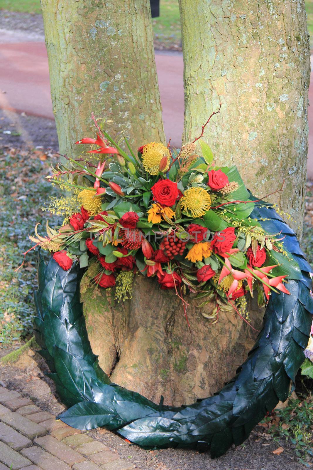 Big sympathy wreath near a tree, red and yellow flowers