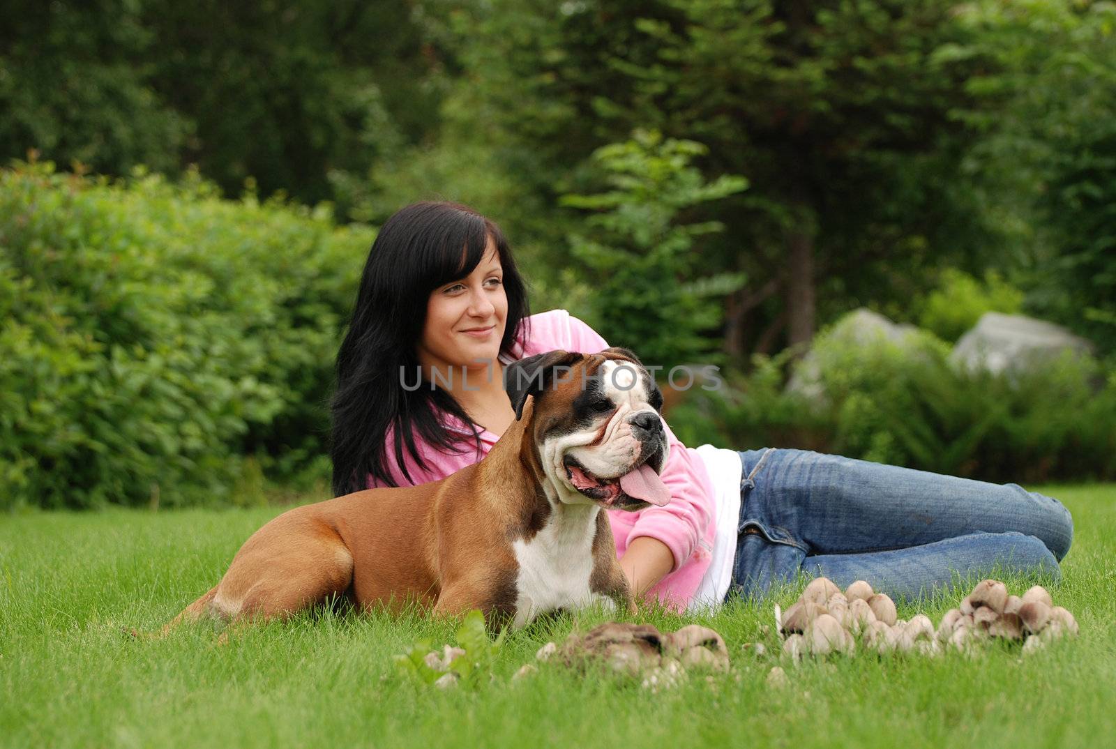 The girl with a dog sit on a grass before them mushrooms grow