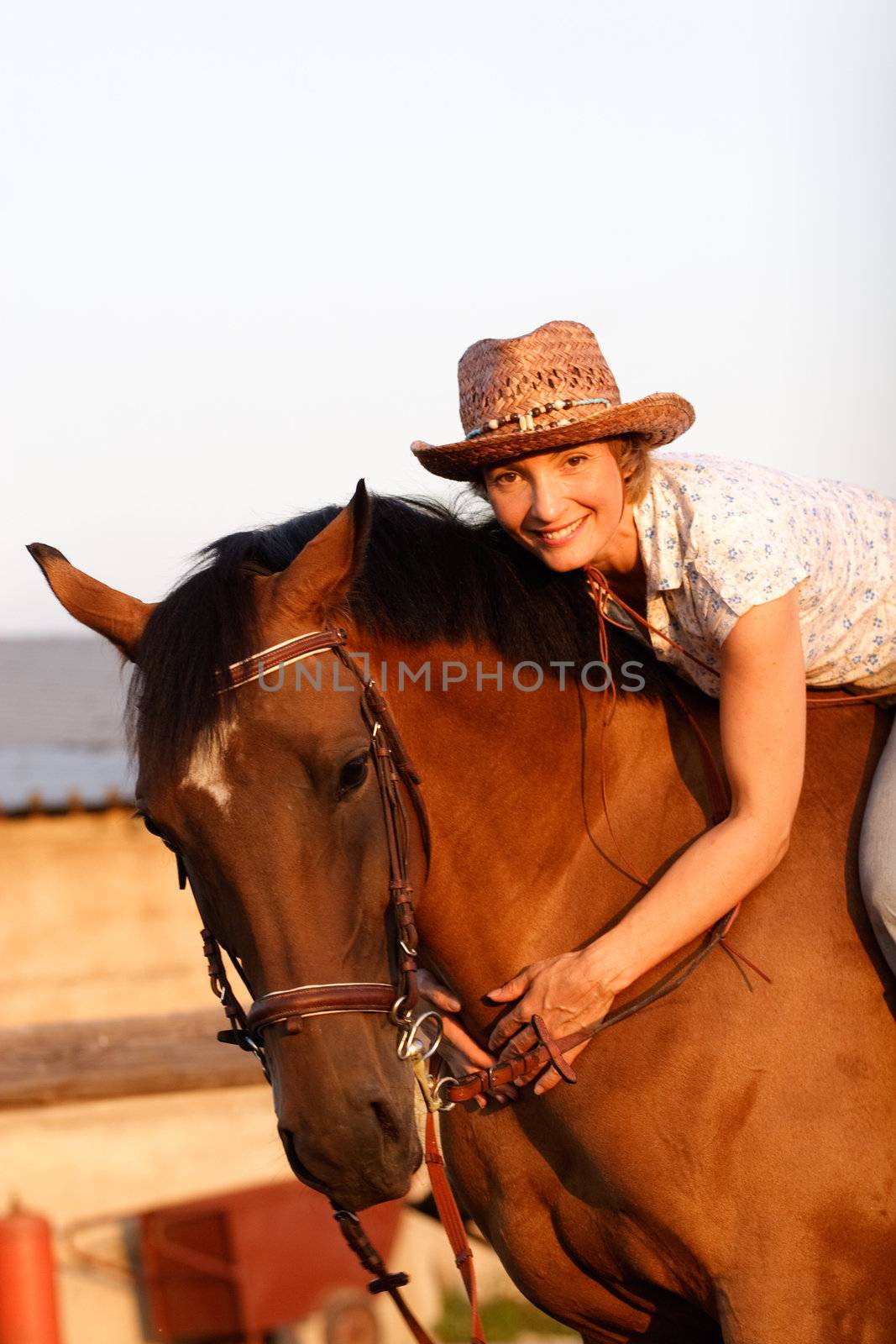 Woman in hat lying on brown horses neck