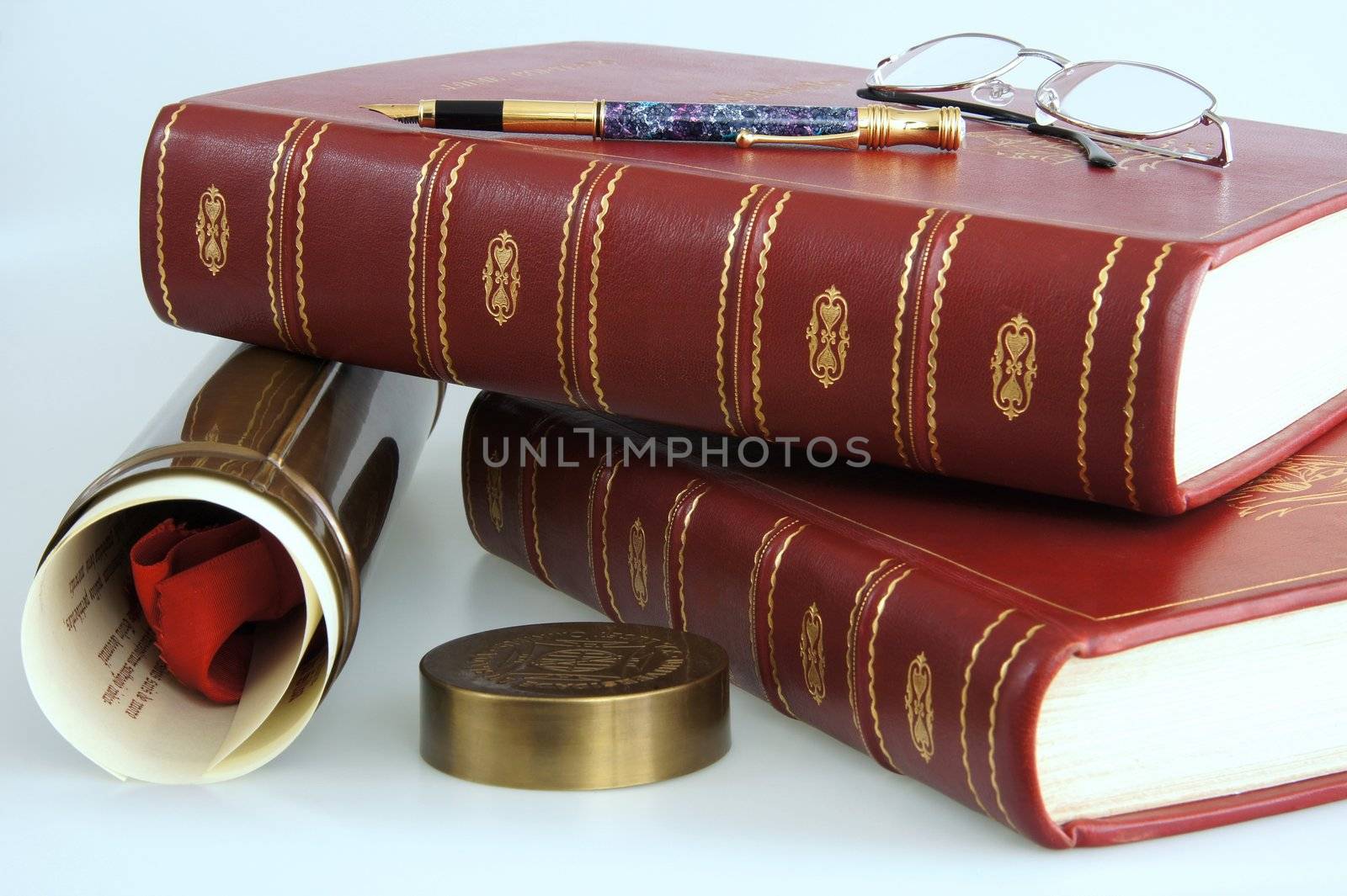 Books and graduation Diploma with a pen and glasses on top