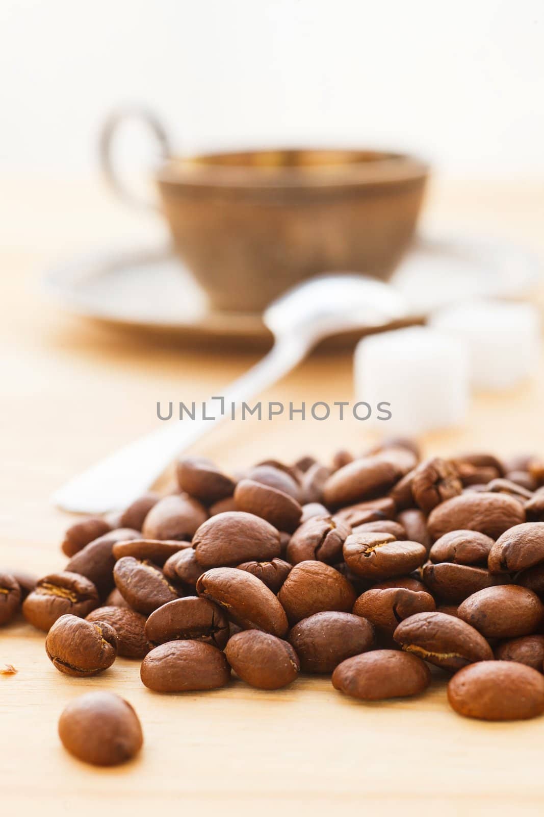 Coffee beans with a cup of coffee in the background. Vertical view