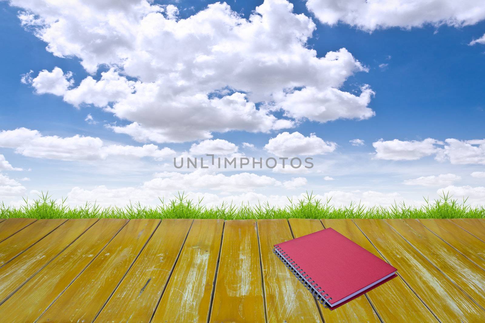 red notebook on wood floor by tungphoto