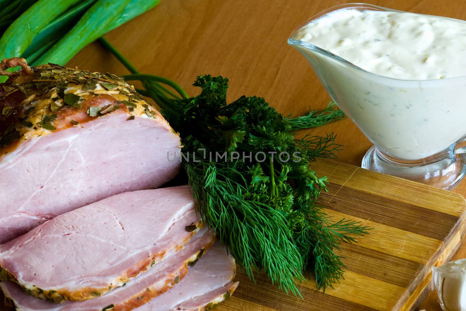 Slices of ham, potherbs and salad of green vegetables on the kitchen table