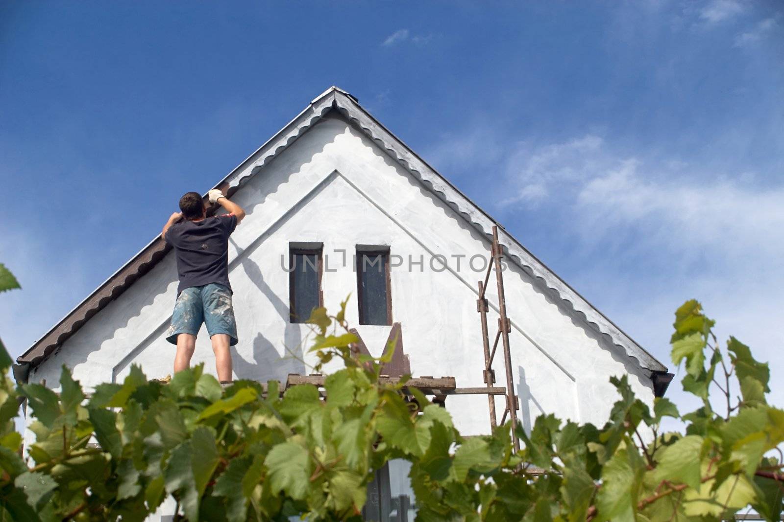 The man paints a roof of the house
