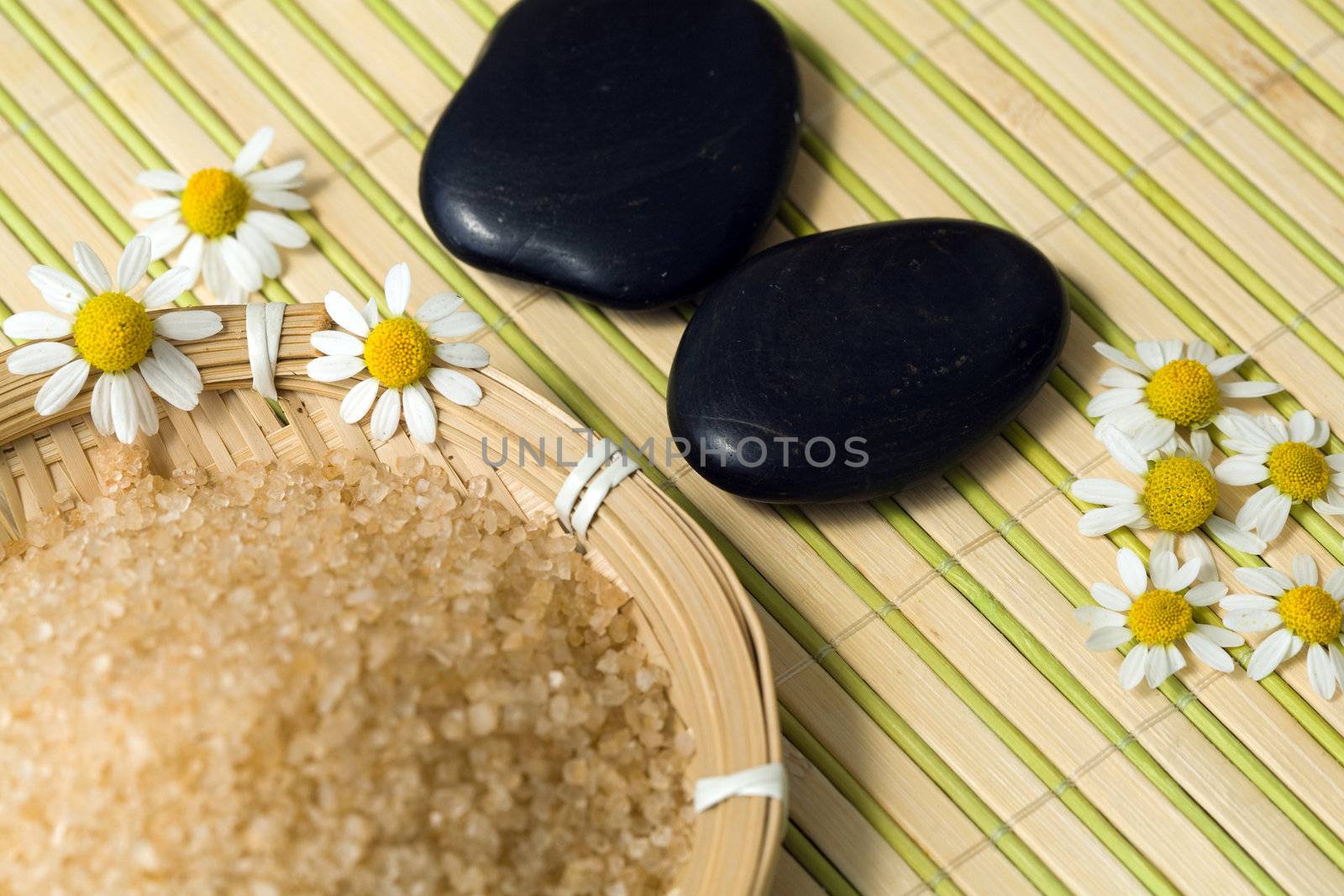 An image of bathing salt with stones and chamomiles