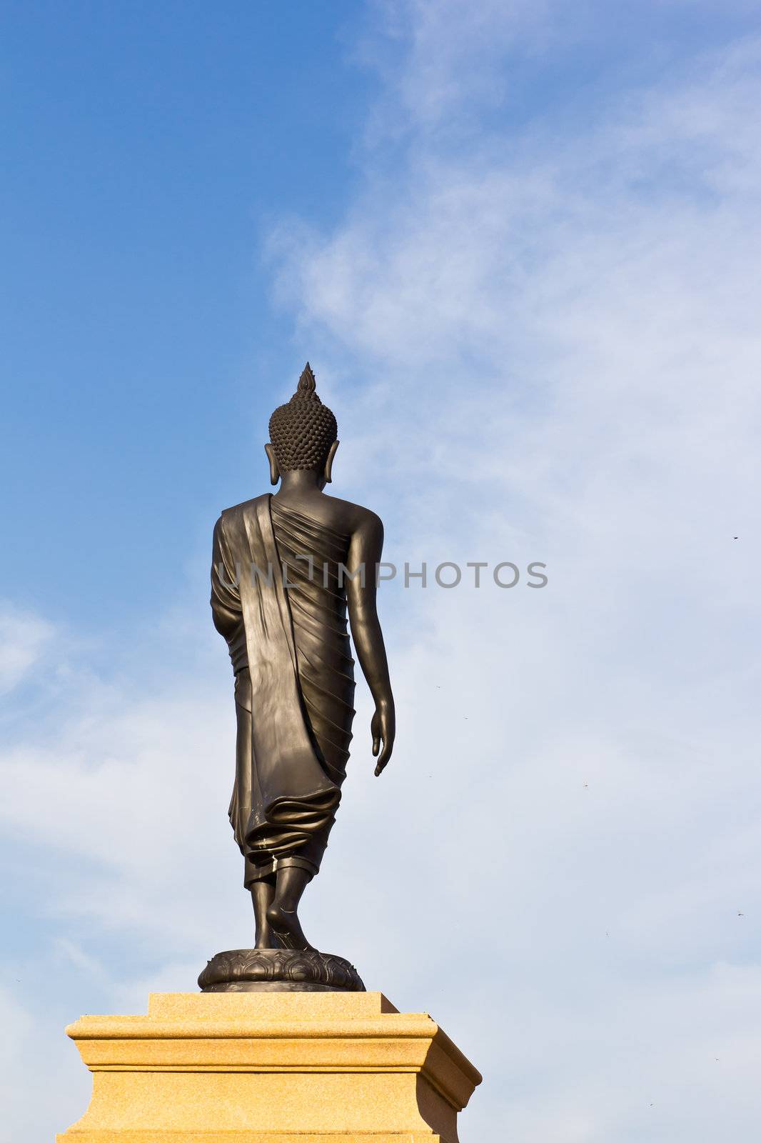 back of black buddha statue against blue sky in thai temple