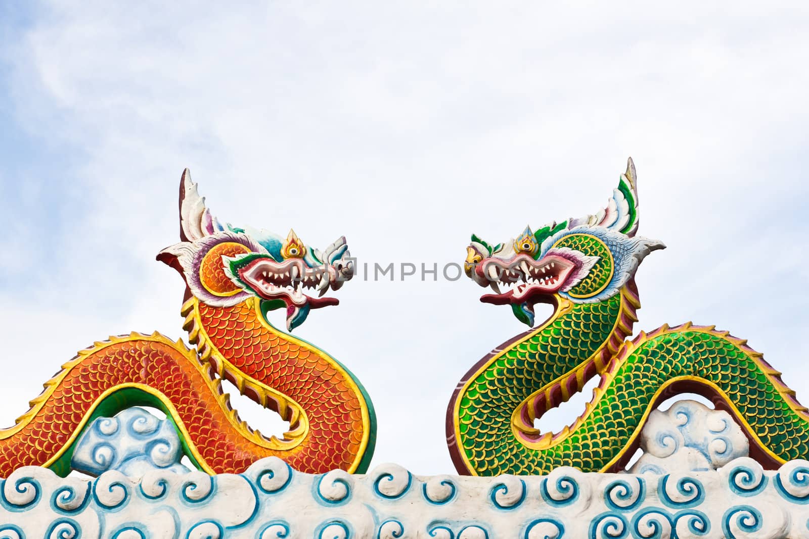 Green and red naga statue against blue sky by tungphoto