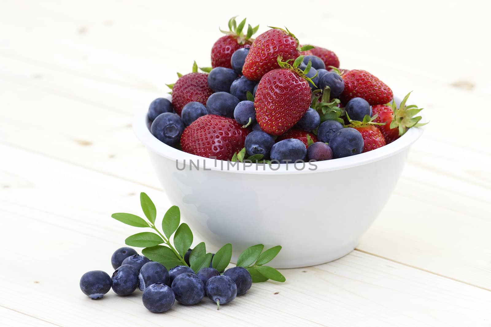Strawberries and blueberries in a white bowl
