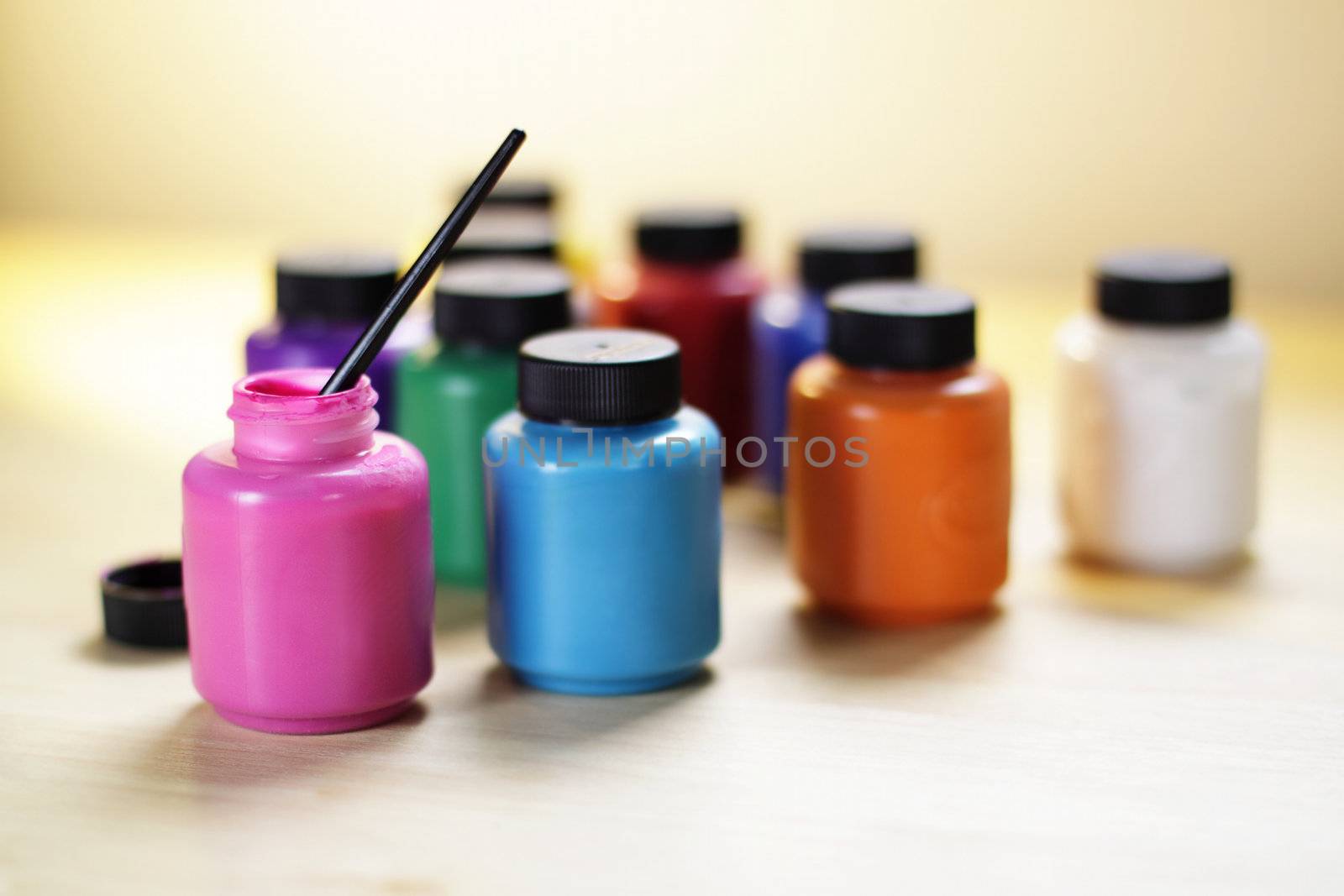 Group of paints in bottles with a small brush, shallow depth of field