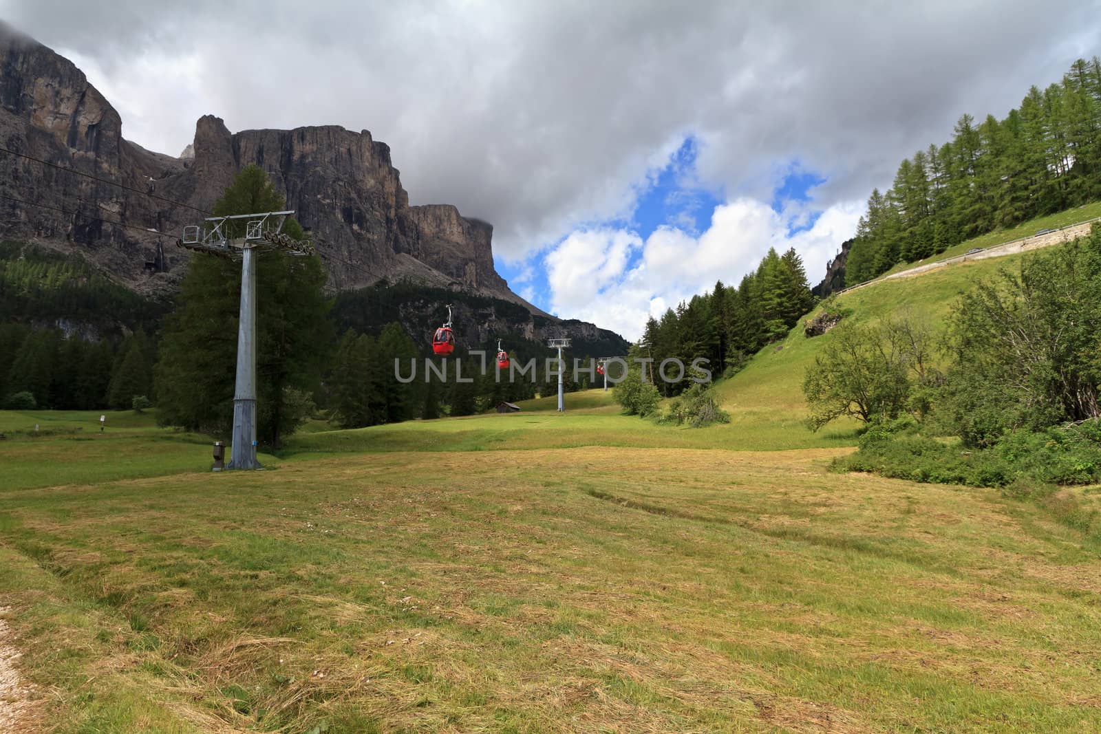 meadow and cableway beneath dolomites peak in Badia Valley, Italy
