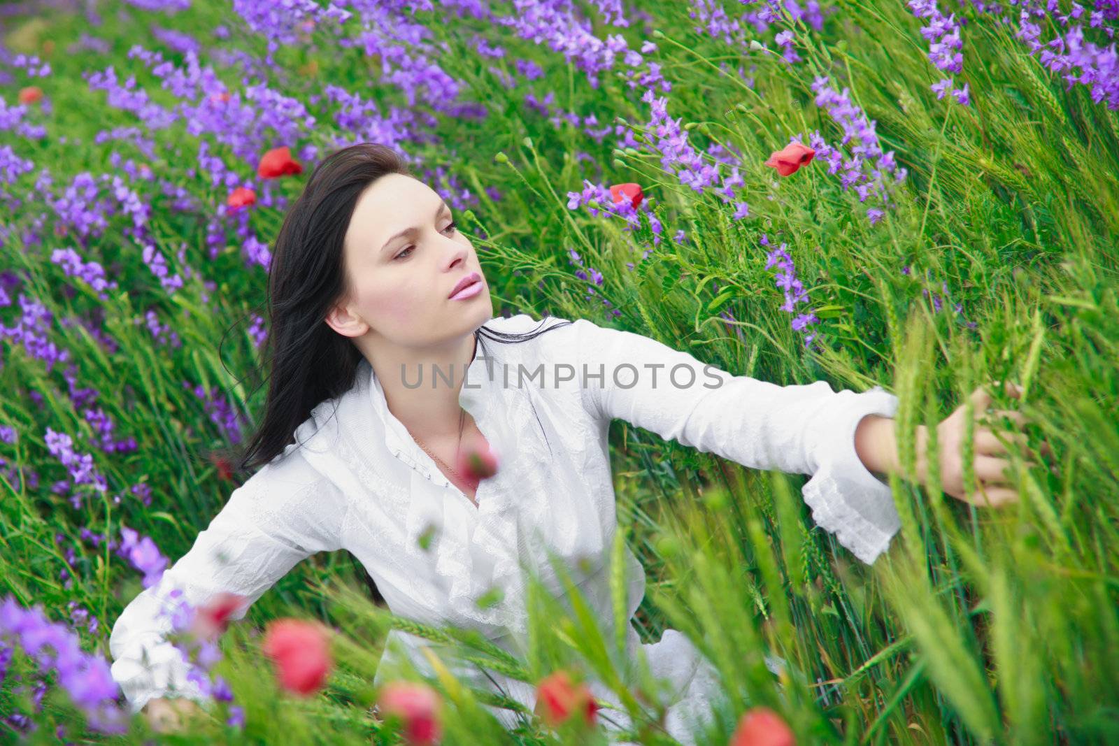 A beautiful young woman smiling, walking in a field of flowers