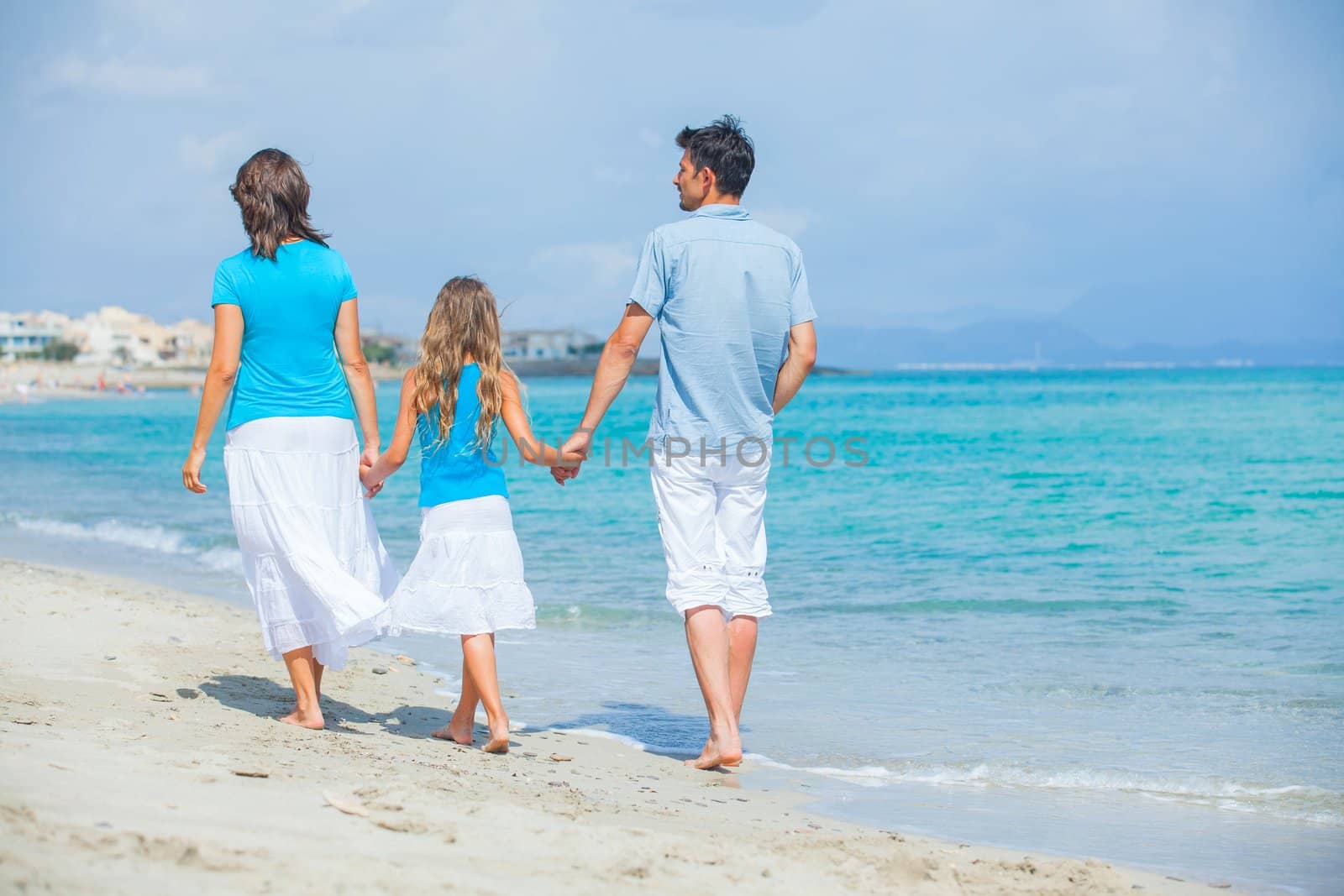 Back view of family of three having fun on tropical beach