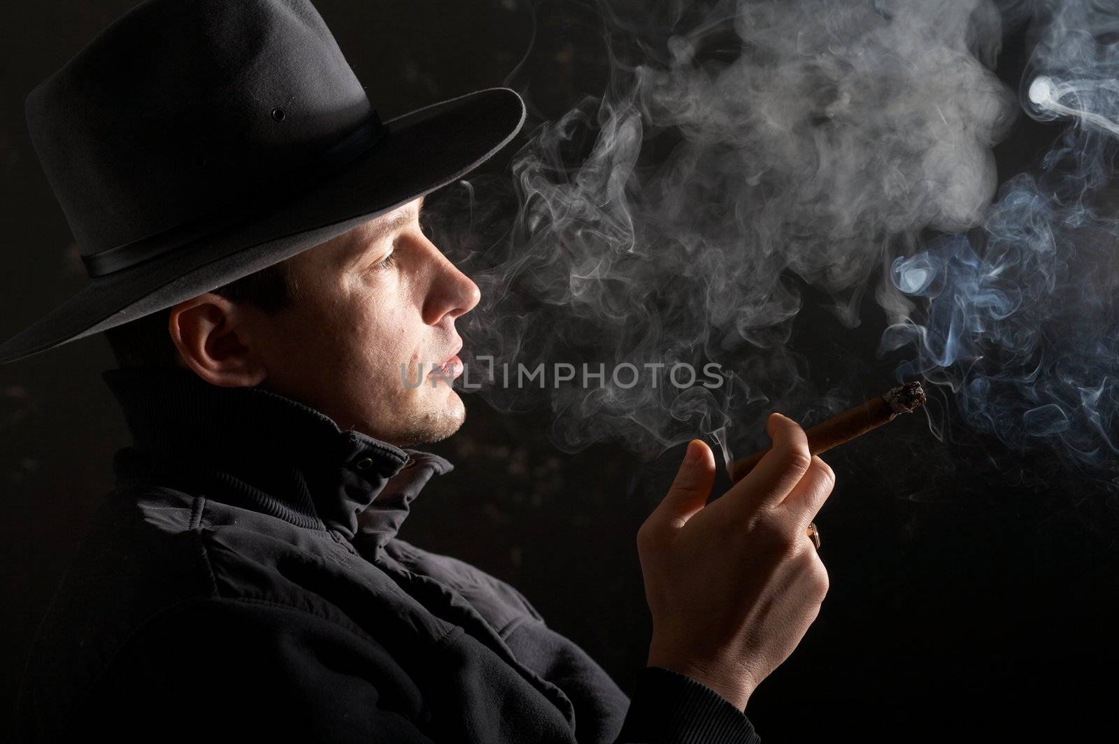 An image of man in felt hat in dark room