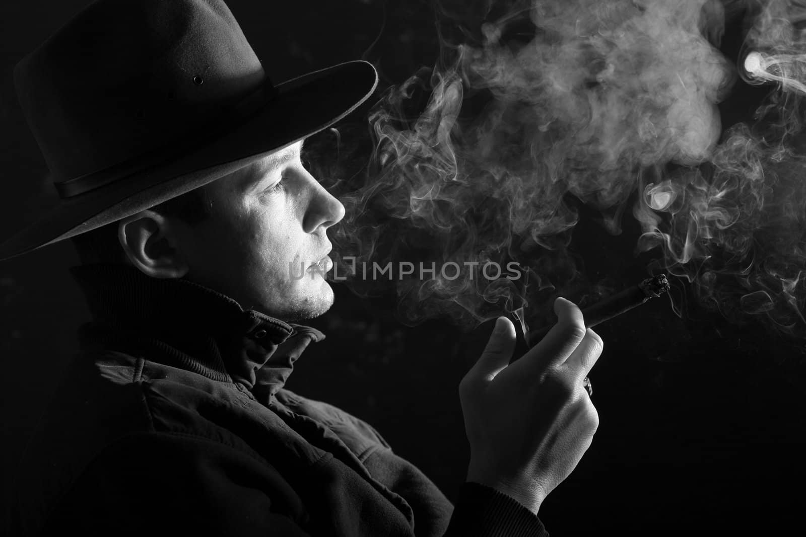 A man in a hat smoking a cigar in puffs of smoke