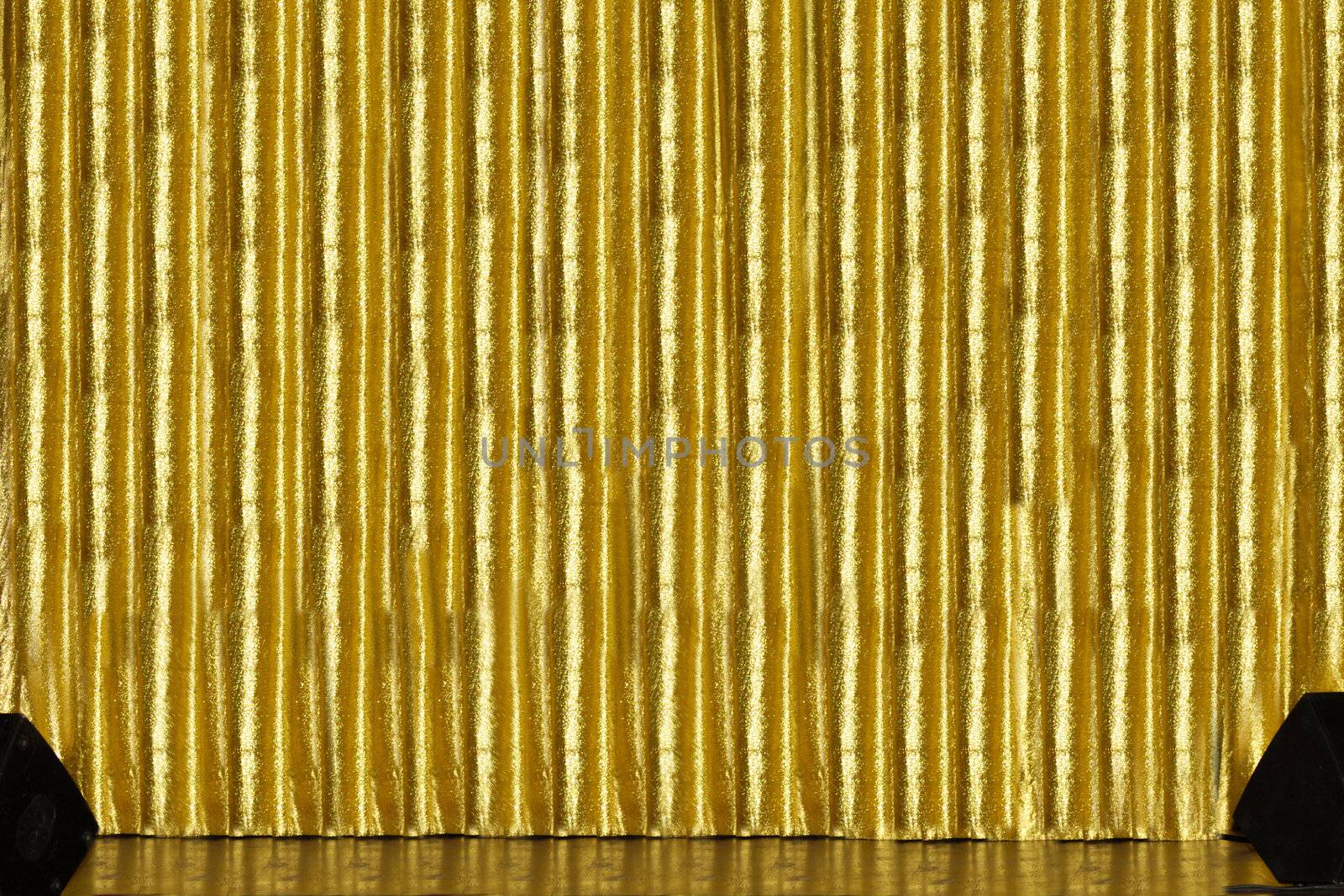 A stage with golden curtain and spakers