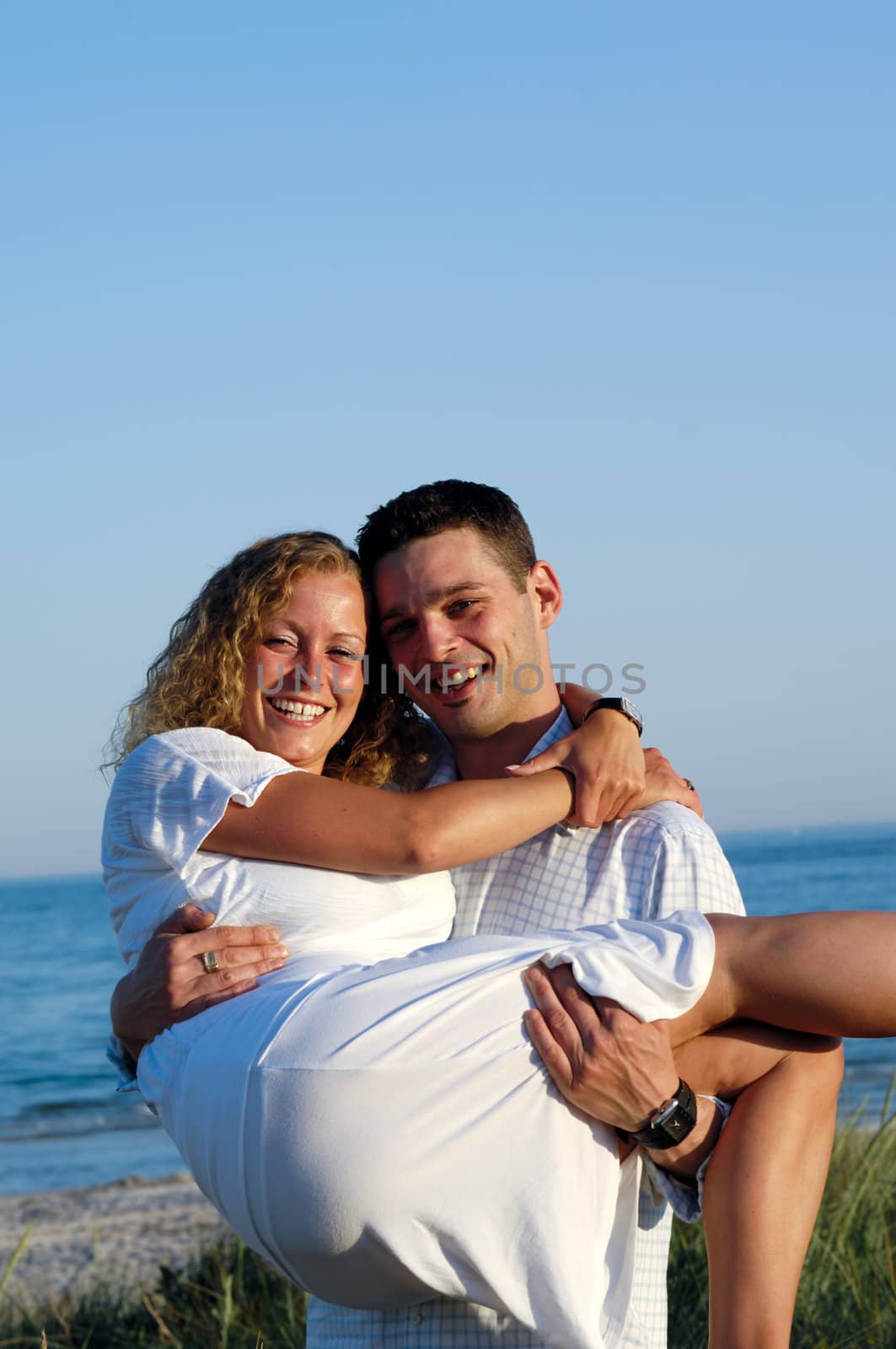 A happy woman and man in love at beach. The the young man is lifting his girlfrind.