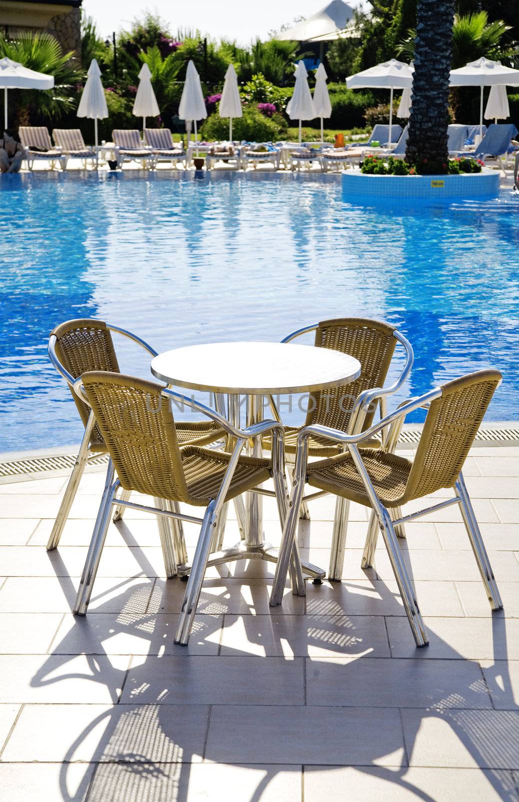 table and chairs near a cool pool in a hot canicular day