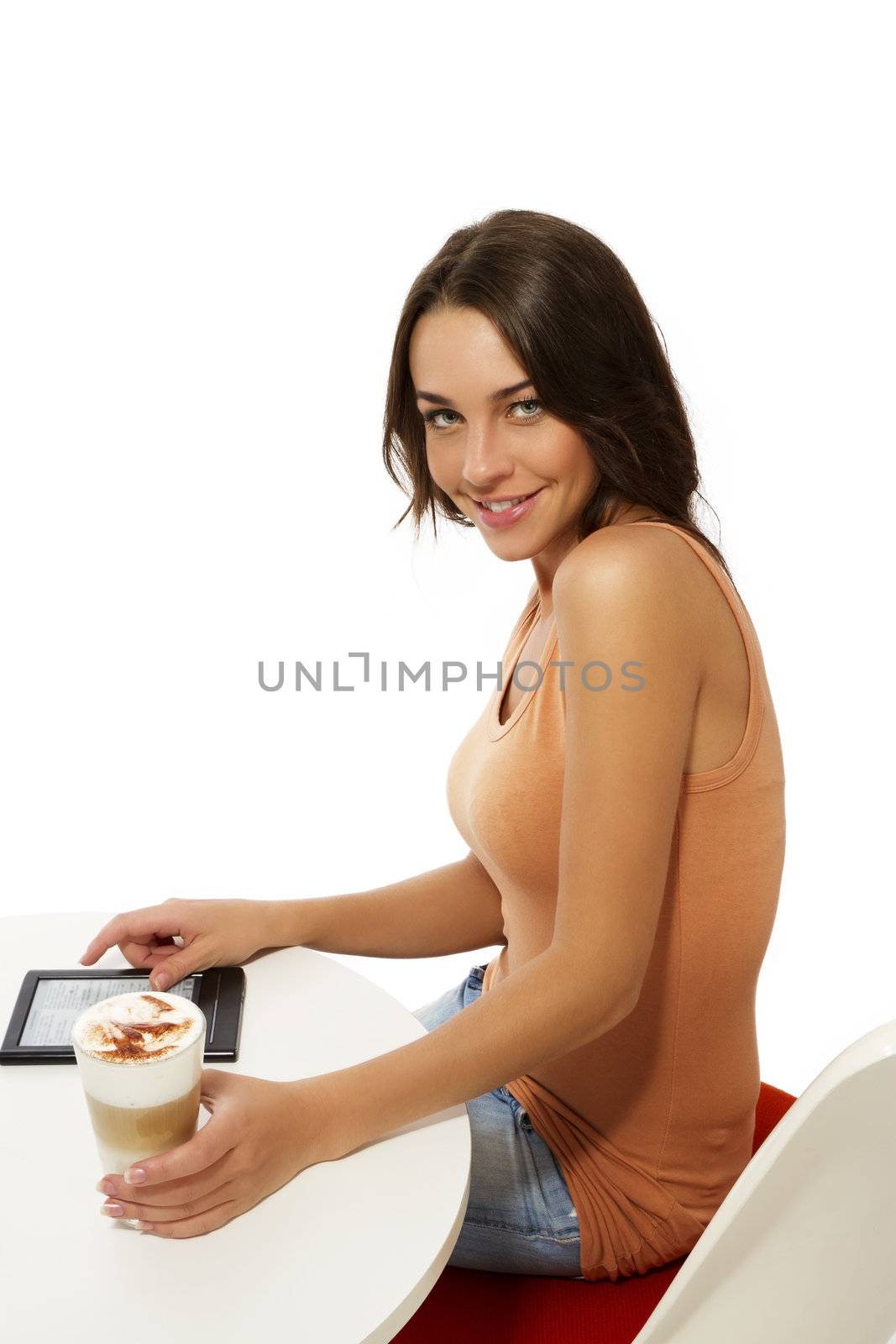 beautiful happy woman sitting at a table with latte macchiato and a ebook reader on white background